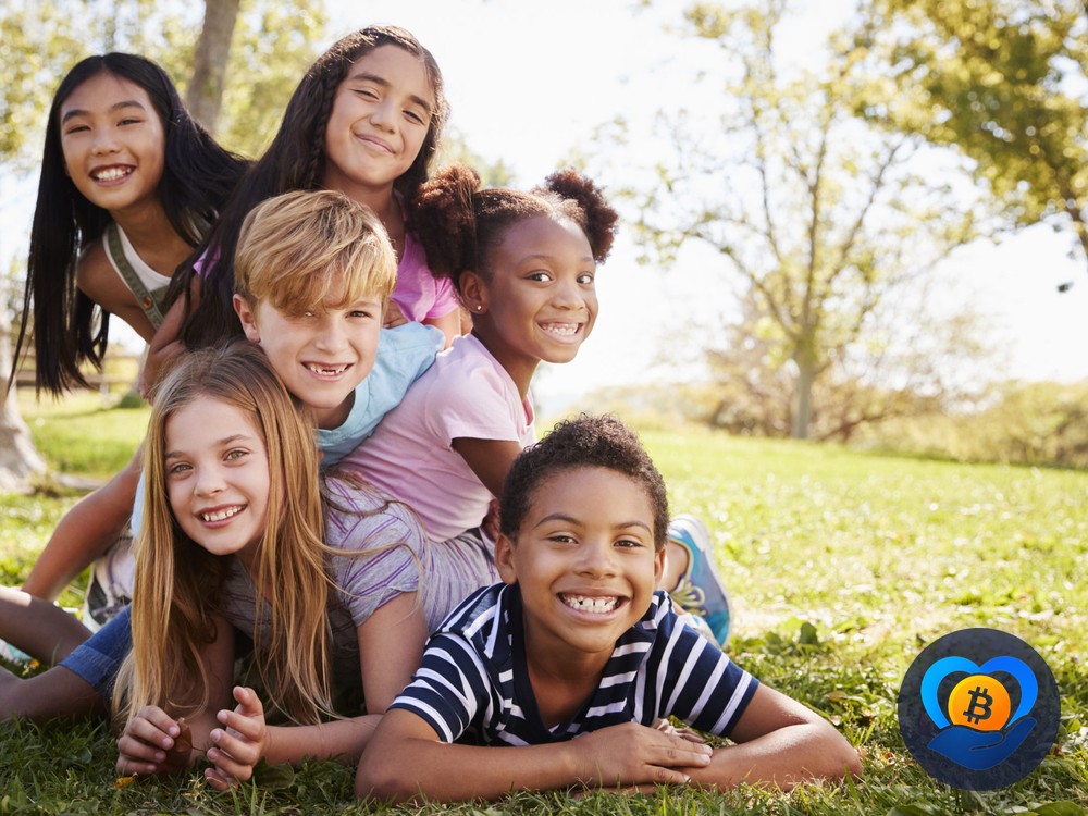 A group of diverse children laughing together outdoors, representing the communities behind DonateCrypto's causes
